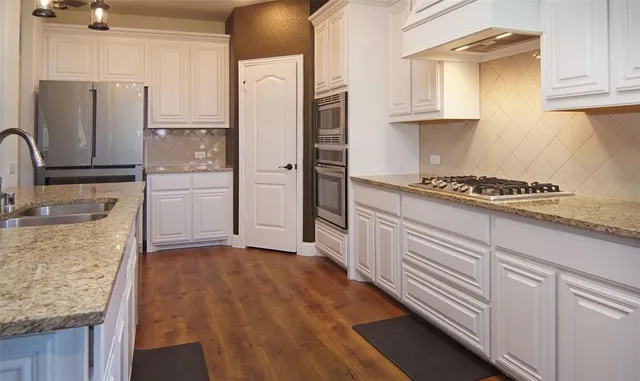a kitchen with stainless steel appliances granite countertop a refrigerator stove and sink