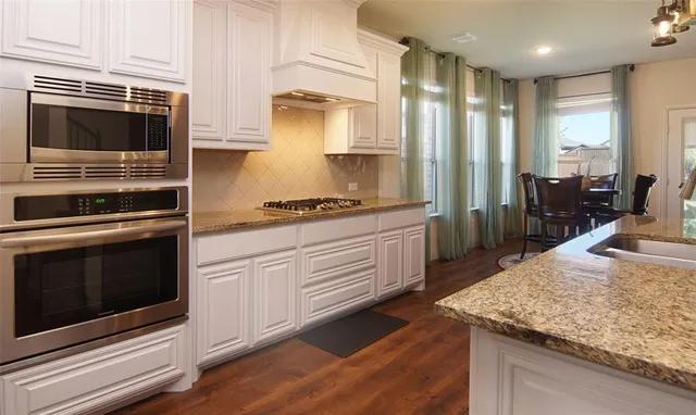 a kitchen with stainless steel appliances kitchen island granite countertop a stove a sink and a microwave