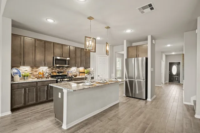 a dining hall with stainless steel appliances kitchen island granite countertop a refrigerator and cabinets