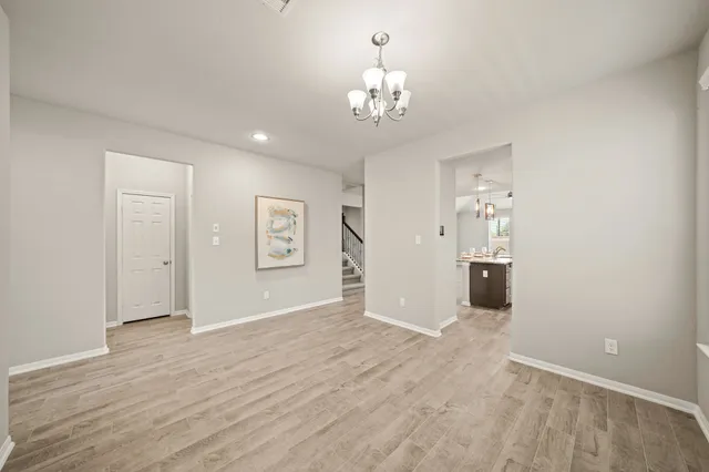 a view of a hallway with wooden floor and chandelier