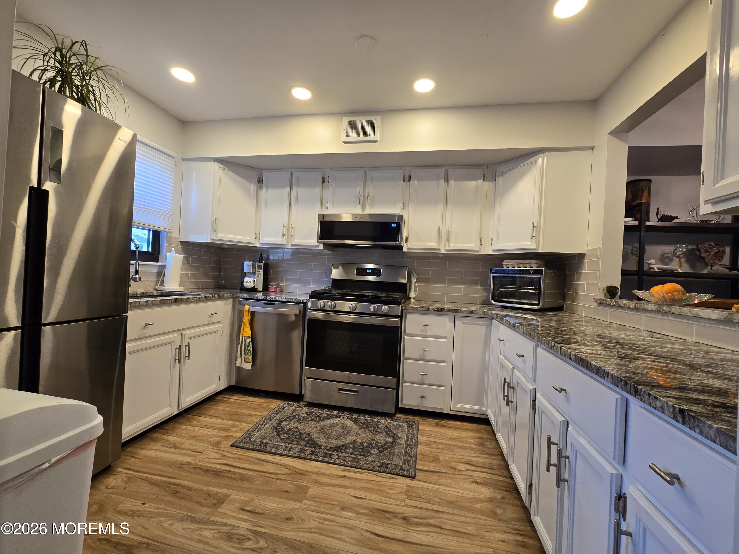 a kitchen with granite countertop a refrigerator stove top oven and sink