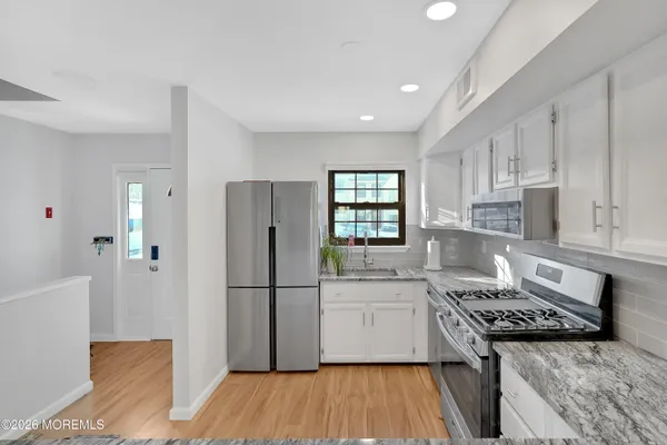 a kitchen with a refrigerator a sink and wooden floor