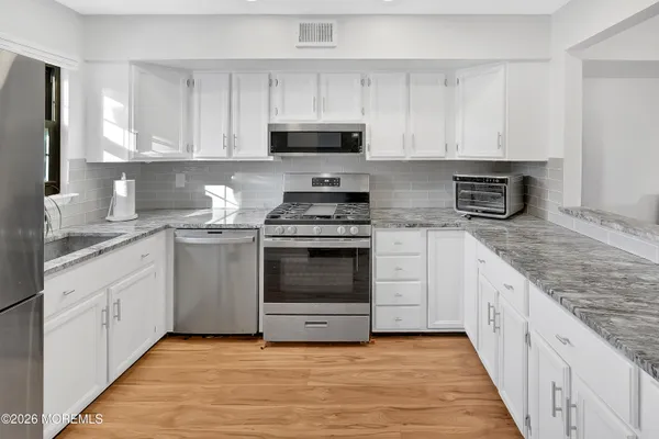 a kitchen with granite countertop white cabinets stainless steel appliances and a sink