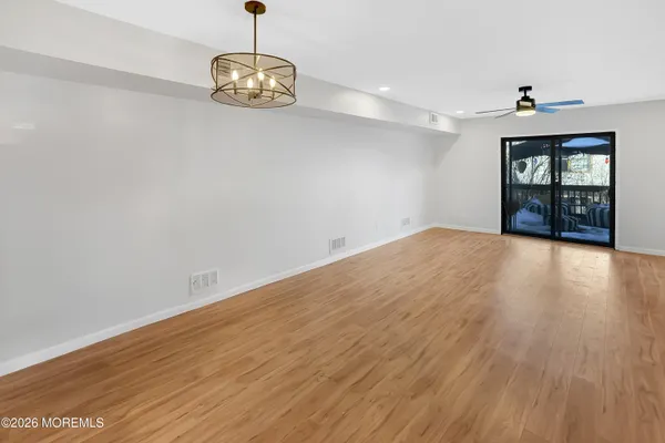 a view of an empty room with window and wooden floor