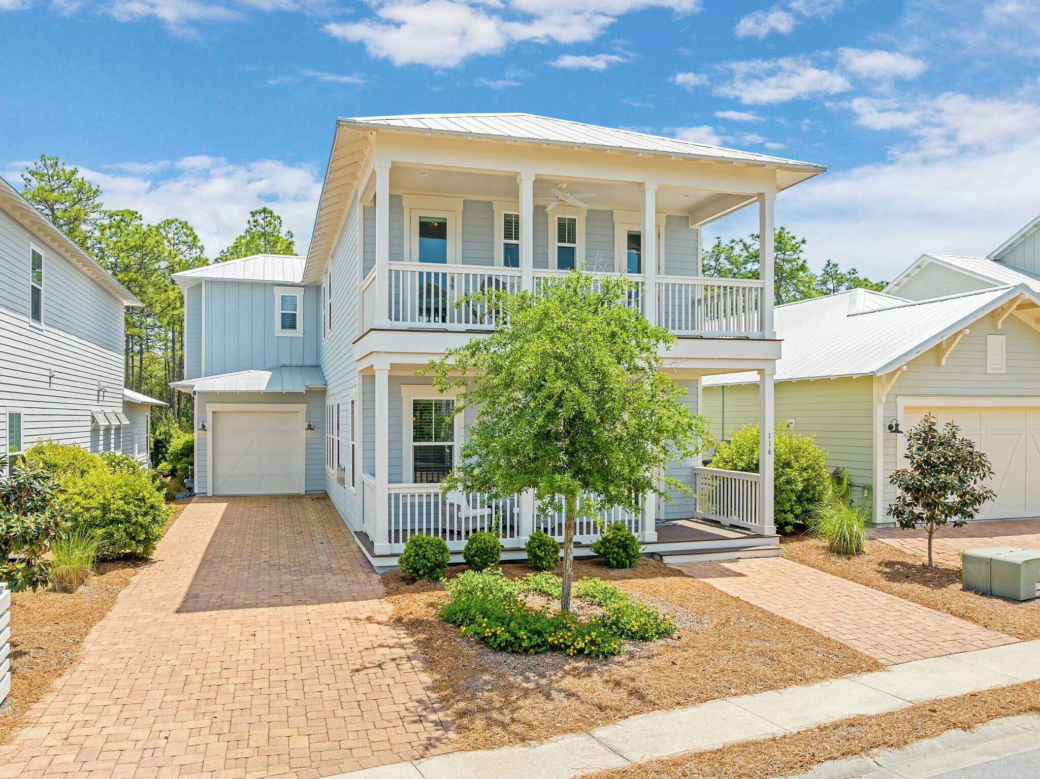 a front view of a house with a yard and potted plants