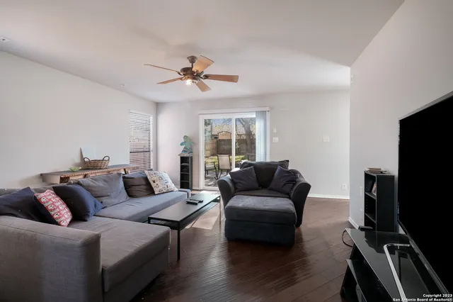 a living room with furniture a ceiling fan and a flat screen tv