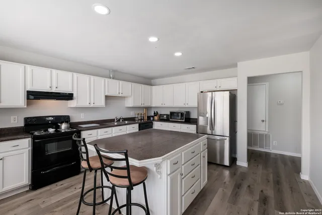 a kitchen with stainless steel appliances granite countertop a refrigerator a stove a sink dishwasher and a refrigerator with wooden floor