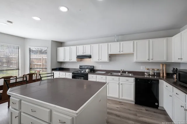 a kitchen with granite countertop a sink a stove and cabinets