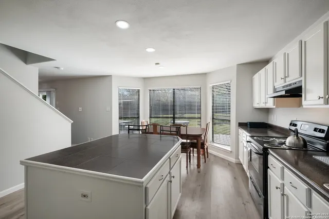 a kitchen with a stove a sink dishwasher and a refrigerator with wooden floor