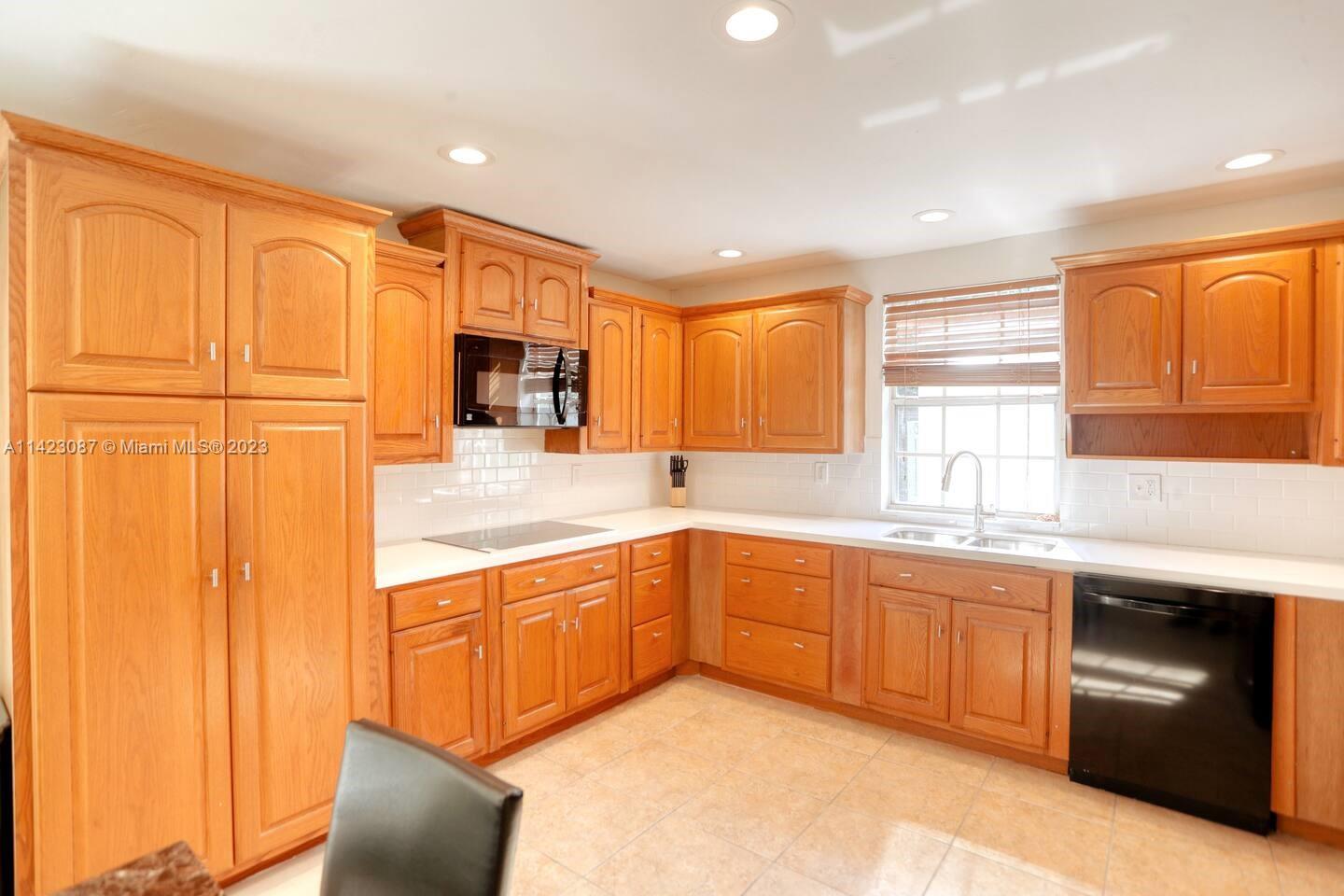 3628 Thomas Avenue Miami, FL 33133 - Photo 4 of 24 a kitchen with stainless steel appliances granite countertop a sink and dishwasher a refrigerator with wooden cabinets