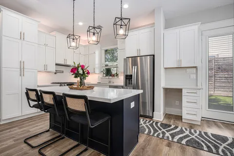 a kitchen with stainless steel appliances kitchen island granite countertop a table chairs and a refrigerator