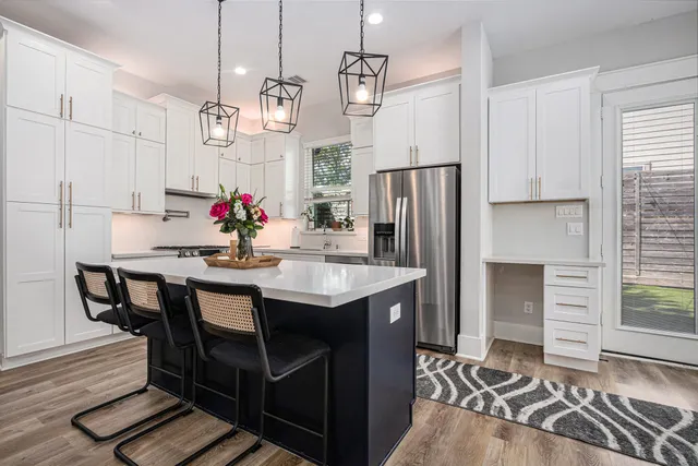 a kitchen with stainless steel appliances kitchen island granite countertop a table chairs and a refrigerator