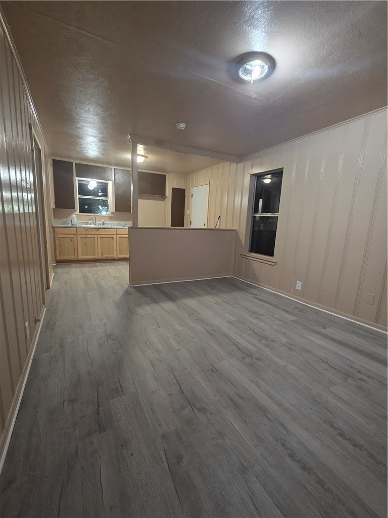 408 North Live Oak Street Mathis, TX 78368 - Photo 3 of 7 an empty room with wooden floor kitchen view and windows