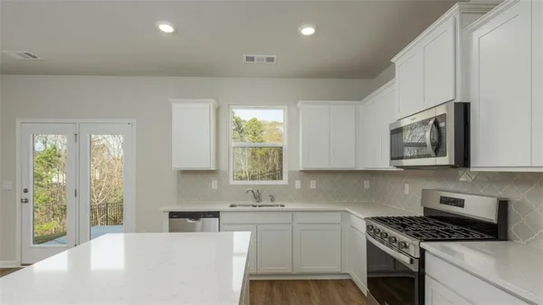 a kitchen with stainless steel appliances granite countertop a sink stove and cabinets