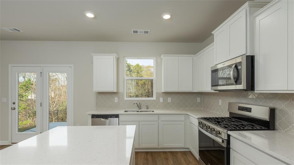2291 Edgecombe Lane Dacula, GA 30019 - Photo 9 of 42 a kitchen with stainless steel appliances granite countertop a sink stove and cabinets