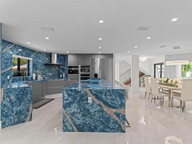 a kitchen with stainless steel appliances kitchen island granite countertop a refrigerator and a stove top oven with wooden floor