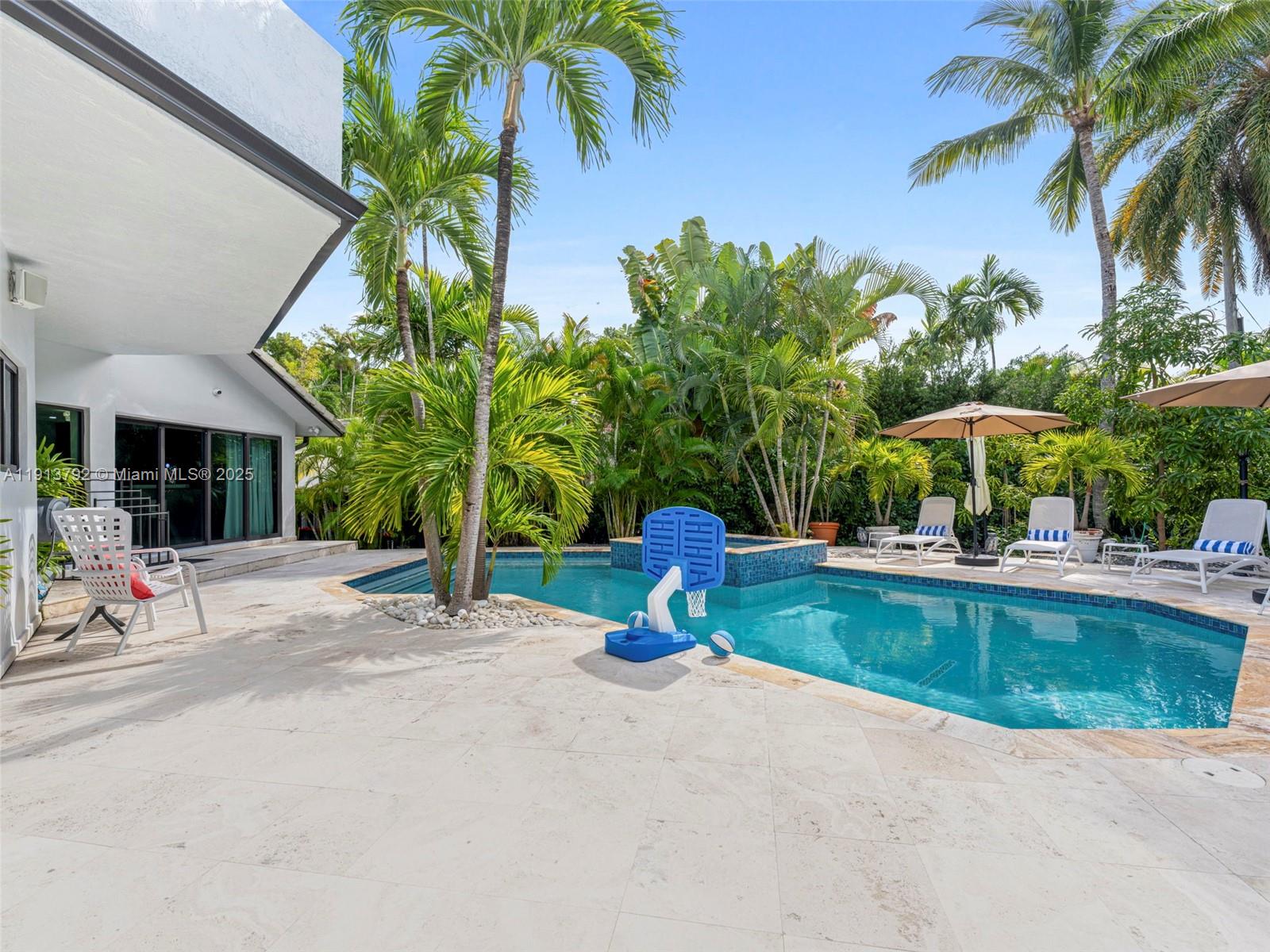 6180 Pine Tree Drive Miami Beach, FL 33140 - Photo 65 of 100 a view of a swimming pool with a lounge chair and palm trees