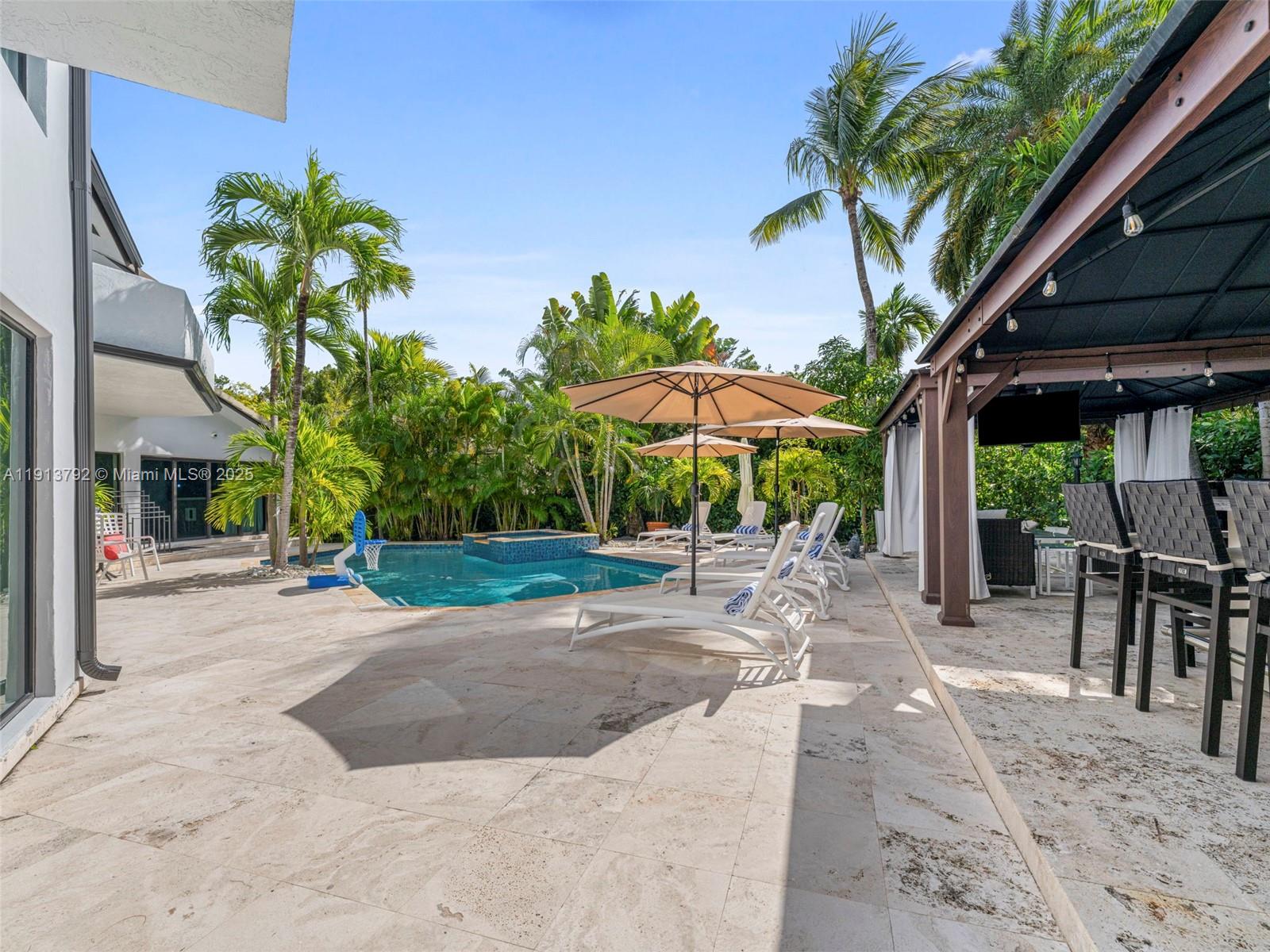 6180 Pine Tree Drive Miami Beach, FL 33140 - Photo 70 of 100 a view of a patio with a table and chairs under an umbrella