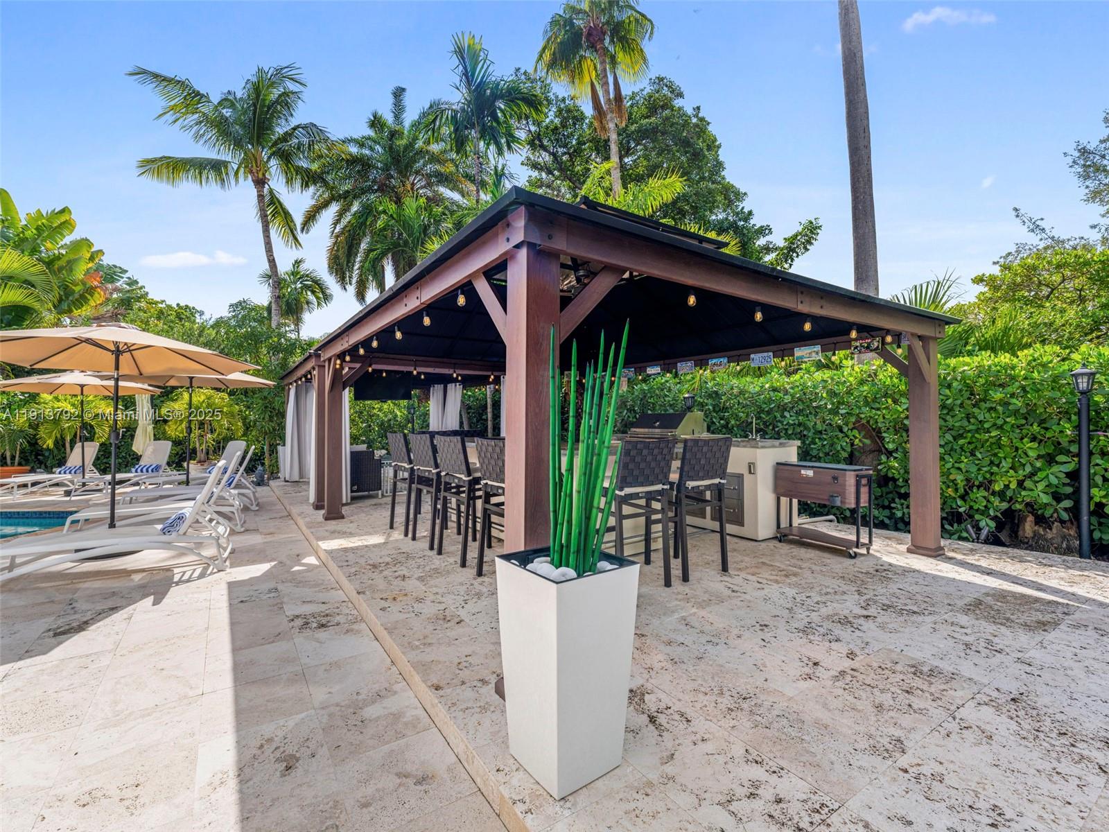 6180 Pine Tree Drive Miami Beach, FL 33140 - Photo 77 of 100 a view of a patio with a table and chairs under an umbrella