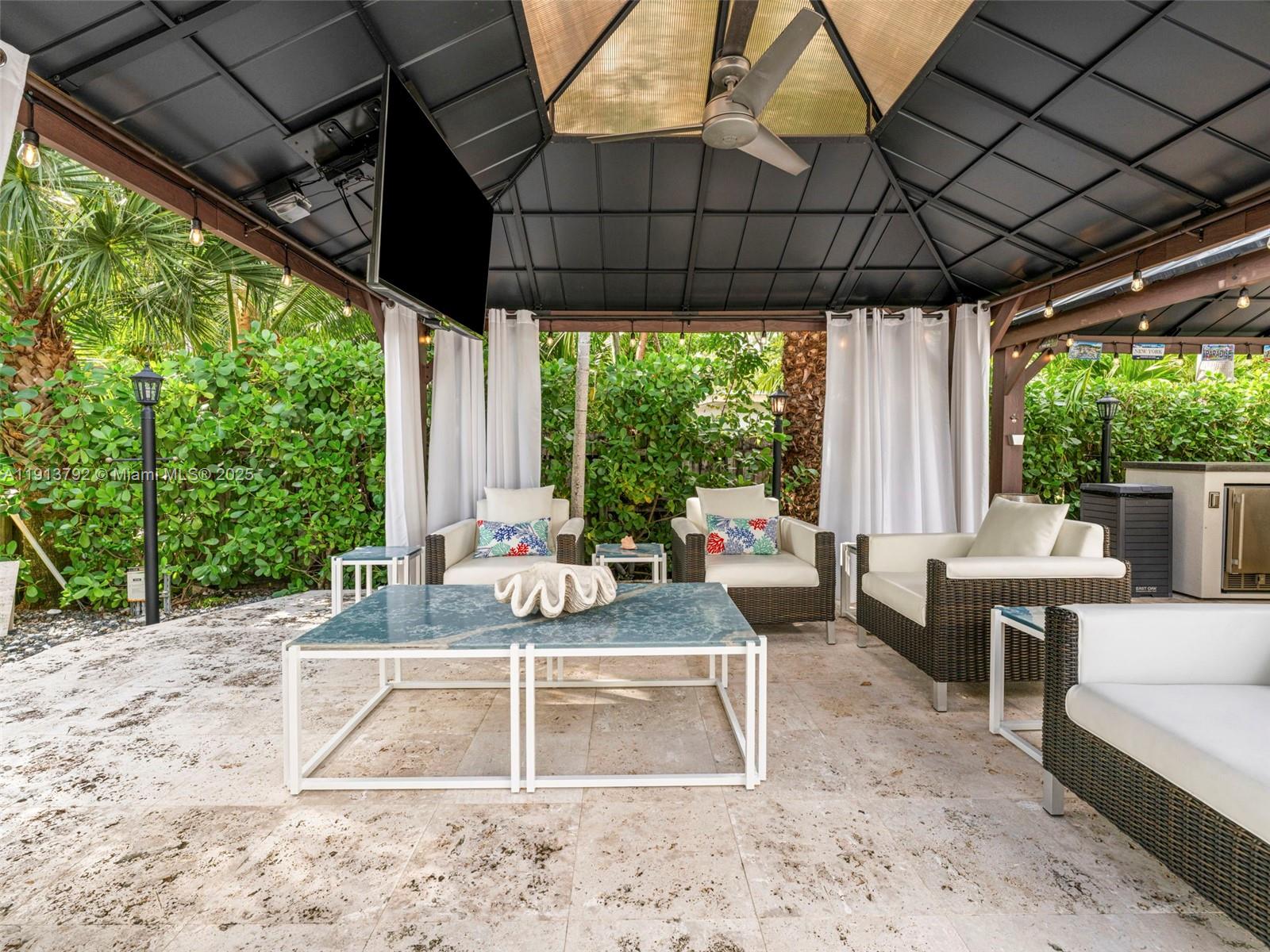 6180 Pine Tree Drive Miami Beach, FL 33140 - Photo 79 of 100 a view of a patio with table and chairs potted plants with the floor to ceiling window