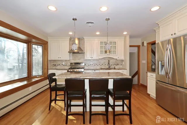 a kitchen with stainless steel appliances granite countertop a table chairs refrigerator and sink
