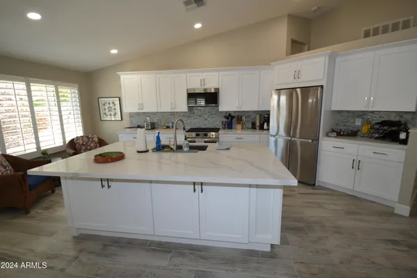 a kitchen with stainless steel appliances a stove a sink a refrigerator a center island and furniture