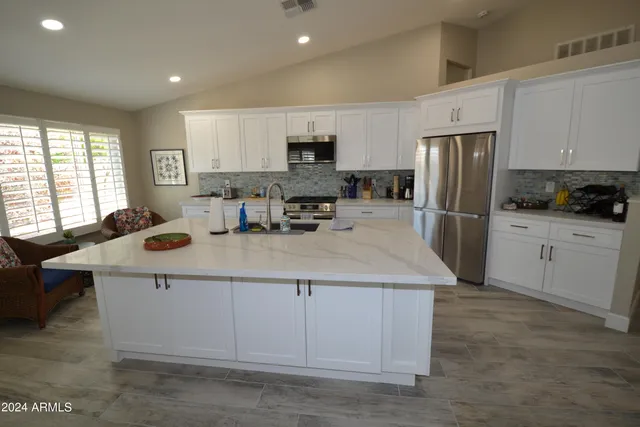 a kitchen with stainless steel appliances a stove a sink a refrigerator a center island and furniture