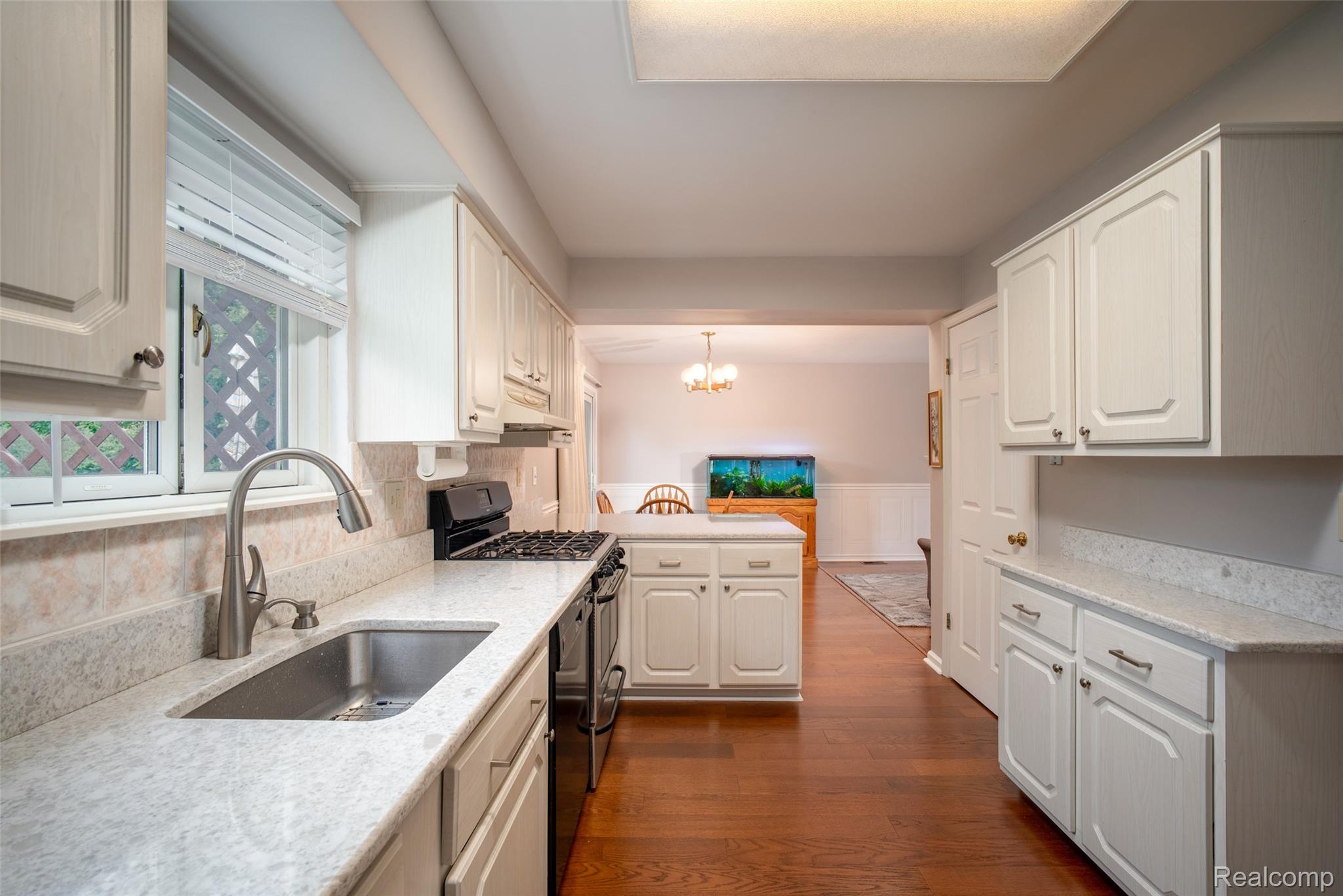 Kitchen featuring white cabinetry, stone countertops, stainless steel sink with pull-down faucet, a gas range, and wood-finish flooring