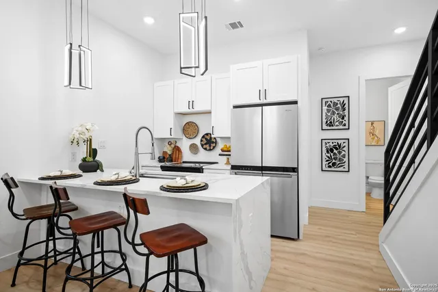 a kitchen with stainless steel appliances a refrigerator a stove a sink and white cabinets with wooden floor