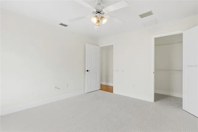 an empty room with a chandelier fan and windows