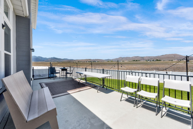1857 Thunder Gulch Road Eagle Mountain, UT 84005 - Photo 45 of 50 Expansive concrete patio featuring a black metal railing and a backdrop of distant hills