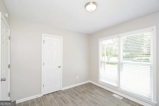 an empty room with wooden floor and windows