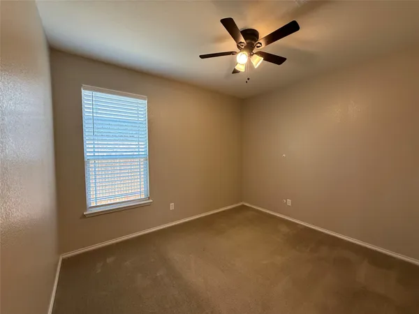 an empty room with a window and a ceiling fan