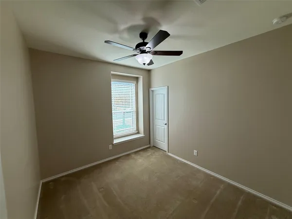 an empty room with a window and a fan