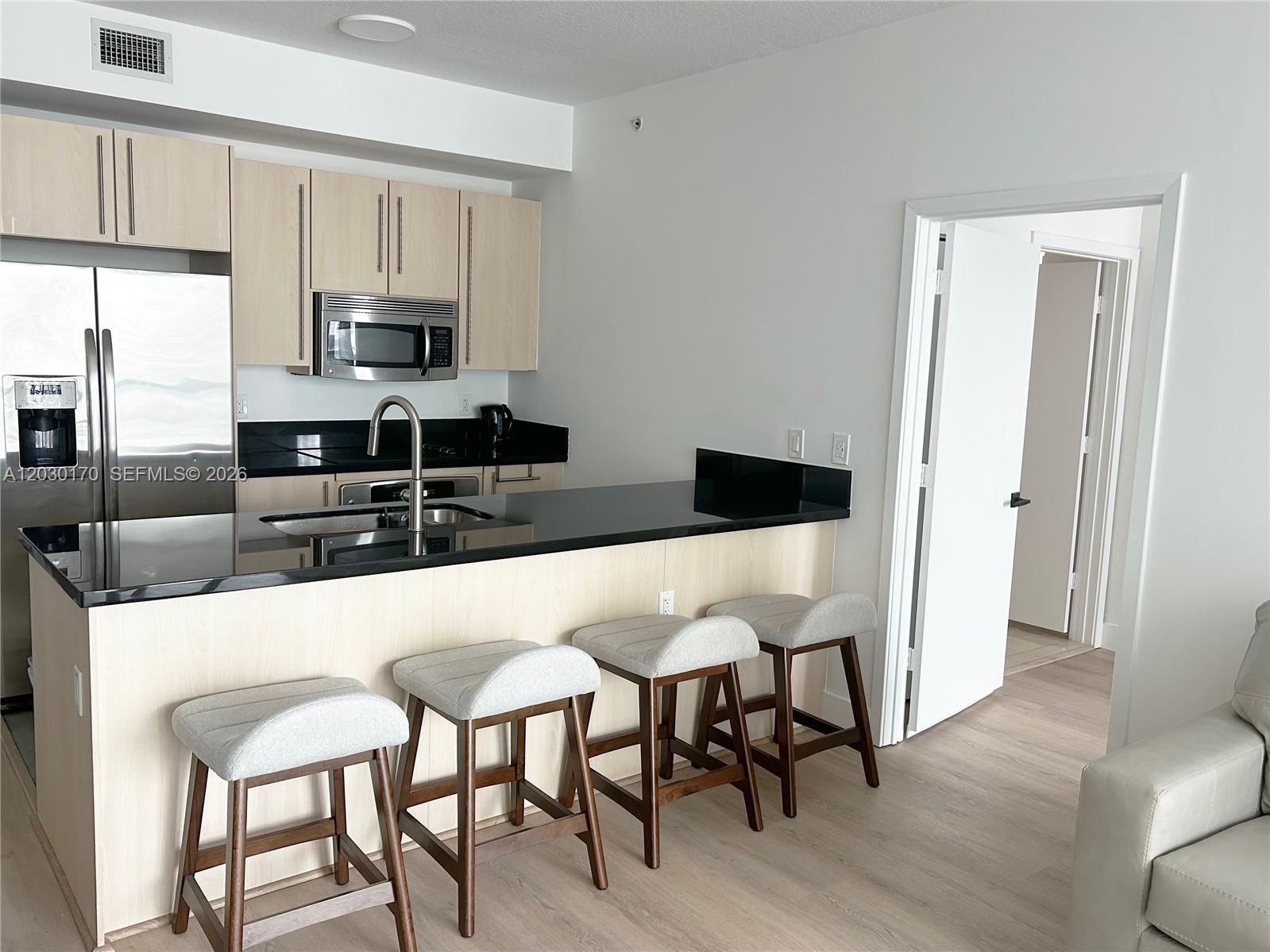 79 Southwest 12th Street, Unit 1710S Miami, FL 33130 - Photo 4 of 25 a kitchen with stainless steel appliances granite countertop a table chairs microwave and sink
