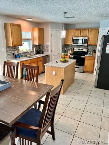 a kitchen with stainless steel appliances granite countertop a stove a sink a dining table and chairs