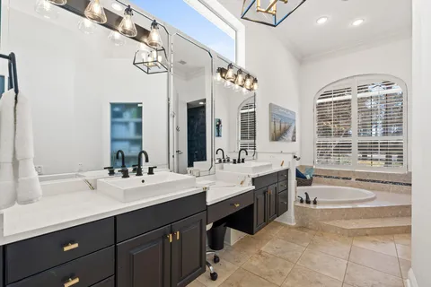 a spacious bathroom with a sink double vanity large mirror and a bathtub