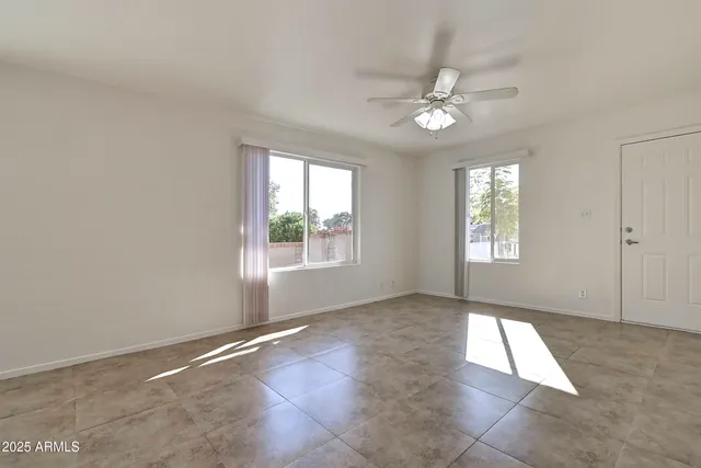 an empty room with windows and fan