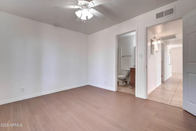 a view of an empty room and a bathroom with sink