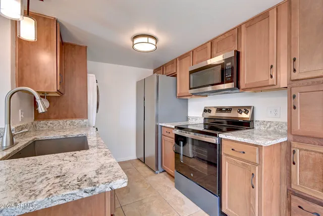 a kitchen with stainless steel appliances granite countertop a stove top oven a sink and a refrigerator