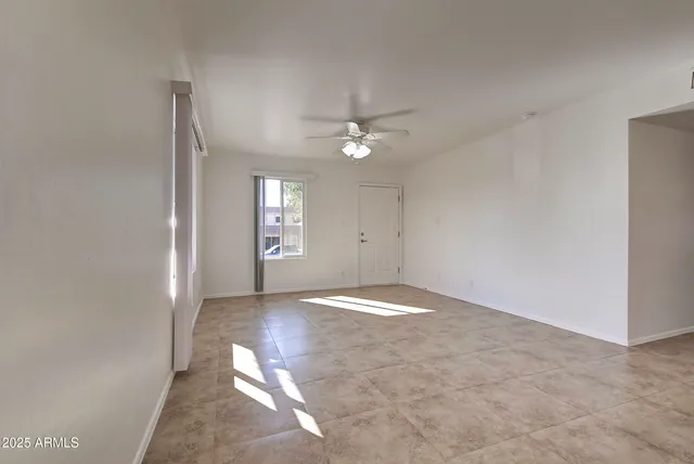 an empty room with fan and windows