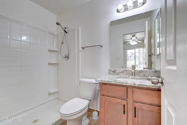 a bathroom with a granite countertop sink toilet a mirror and shower