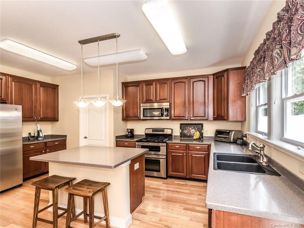2074 Durand Road, Unit 18 Fort Mill, SC 29715 - Photo 9 of 24 a kitchen with granite countertop a stove top oven a sink dishwasher a dining table and chairs with wooden floor