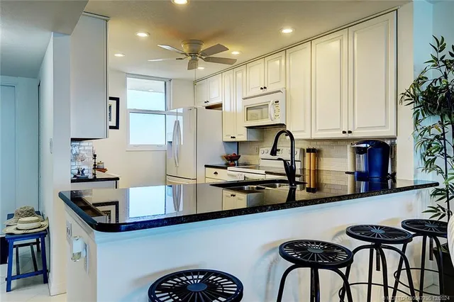 a kitchen with kitchen island granite countertop a sink appliances cabinets and a counter top space