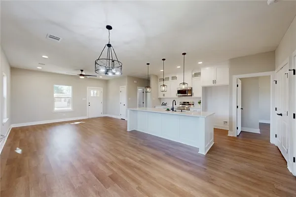 a view of a kitchen with kitchen island a sink wooden floor and stainless steel appliances
