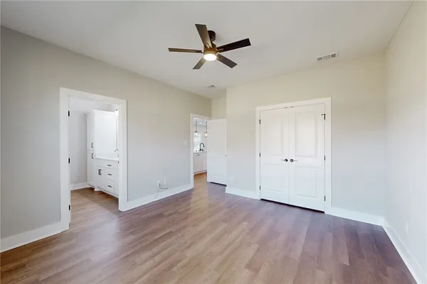 an empty room with wooden floor and a ceiling fan