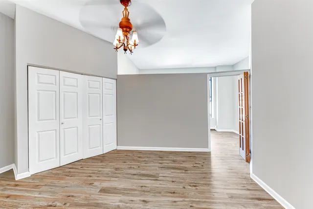 a view of an empty room with wooden floor and chandelier