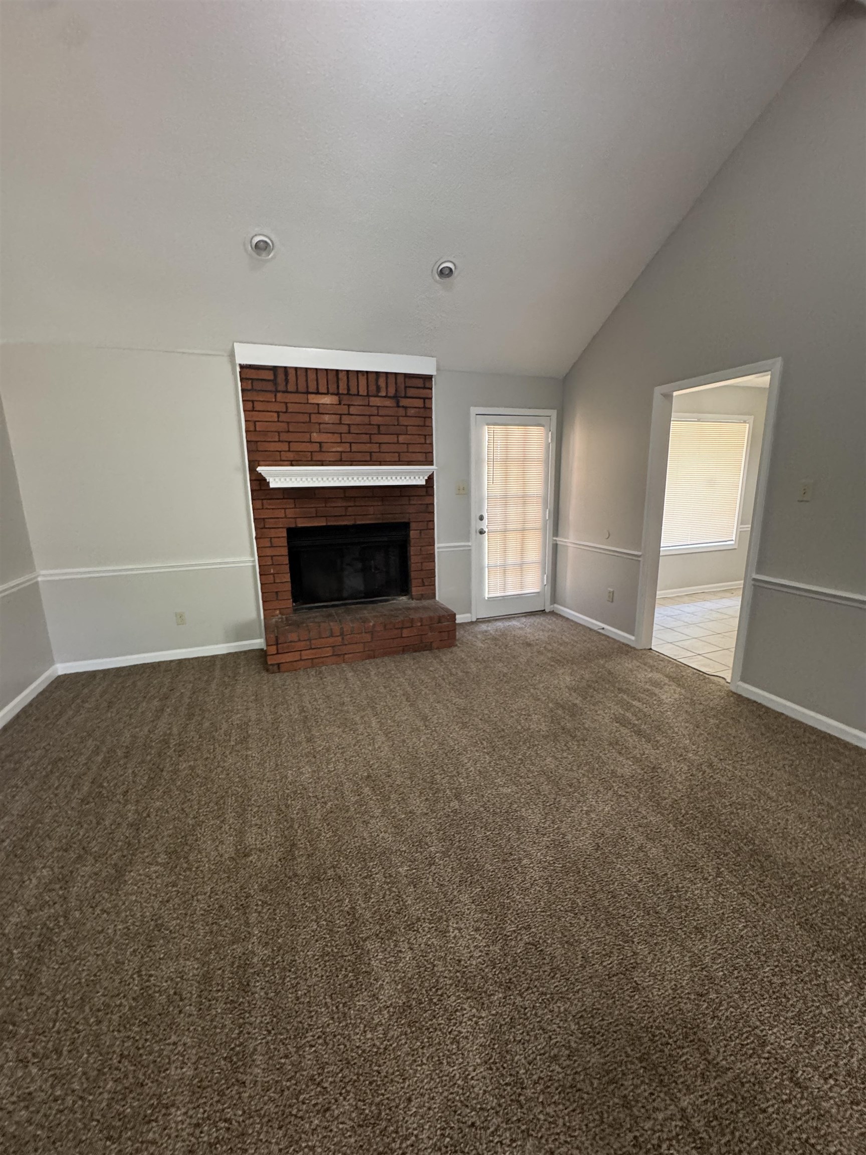 7266 Woodshire Road Memphis, TN 38125 - Photo 14 of 14 Unfurnished living room with dark carpet, a fireplace, and lofted ceiling