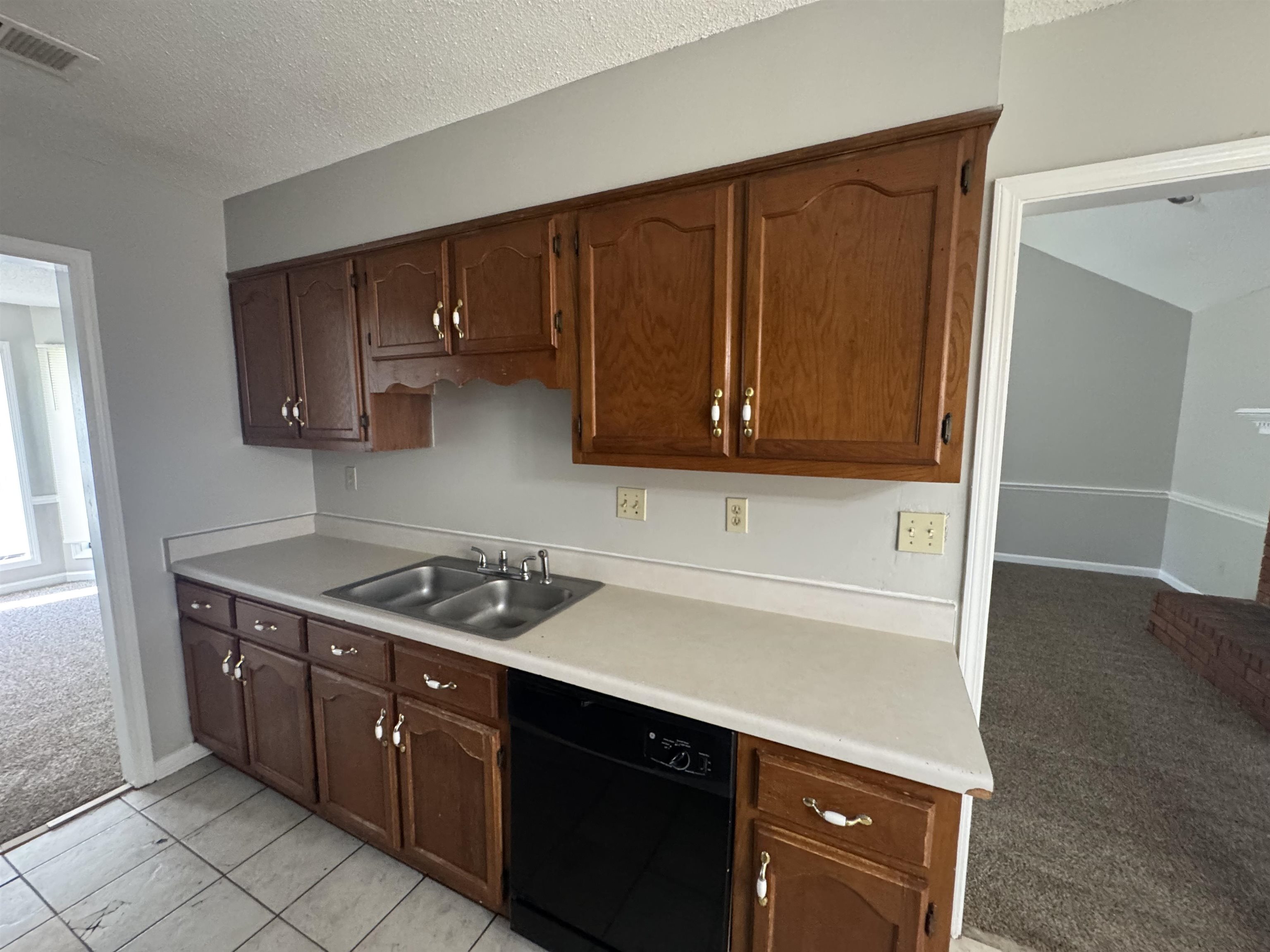 7266 Woodshire Road Memphis, TN 38125 - Photo 3 of 14 Kitchen featuring light carpet, light countertops, dishwasher, a textured ceiling, and light tile patterned floors