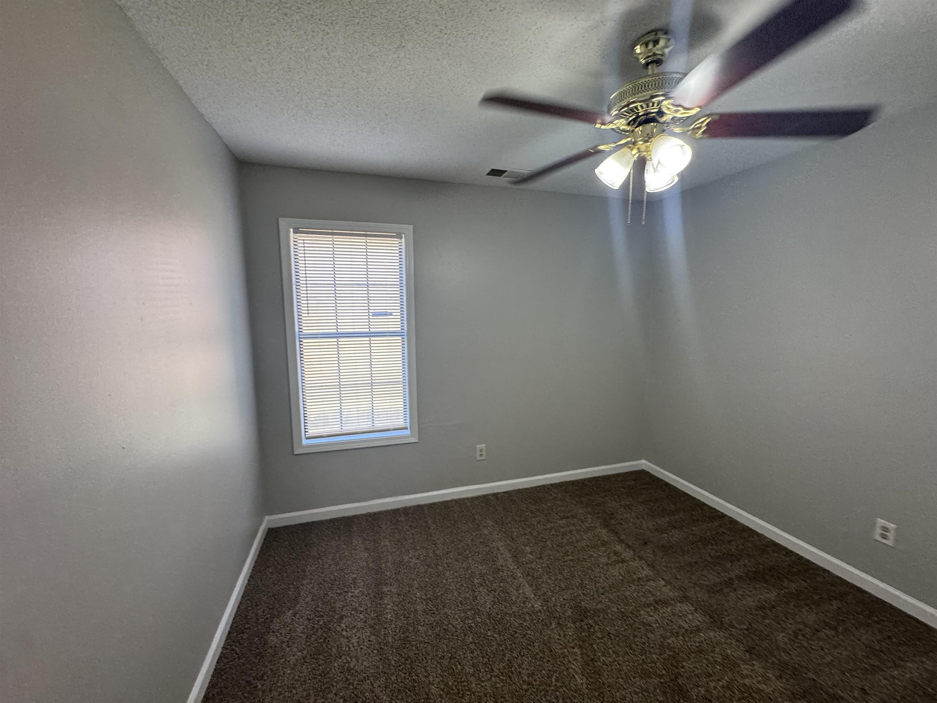 7266 Woodshire Road Memphis, TN 38125 - Photo 7 of 14 Empty room with a textured ceiling, dark carpet, and a ceiling fan